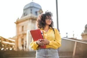 A newly-enrolled student holds her books in front of a school building