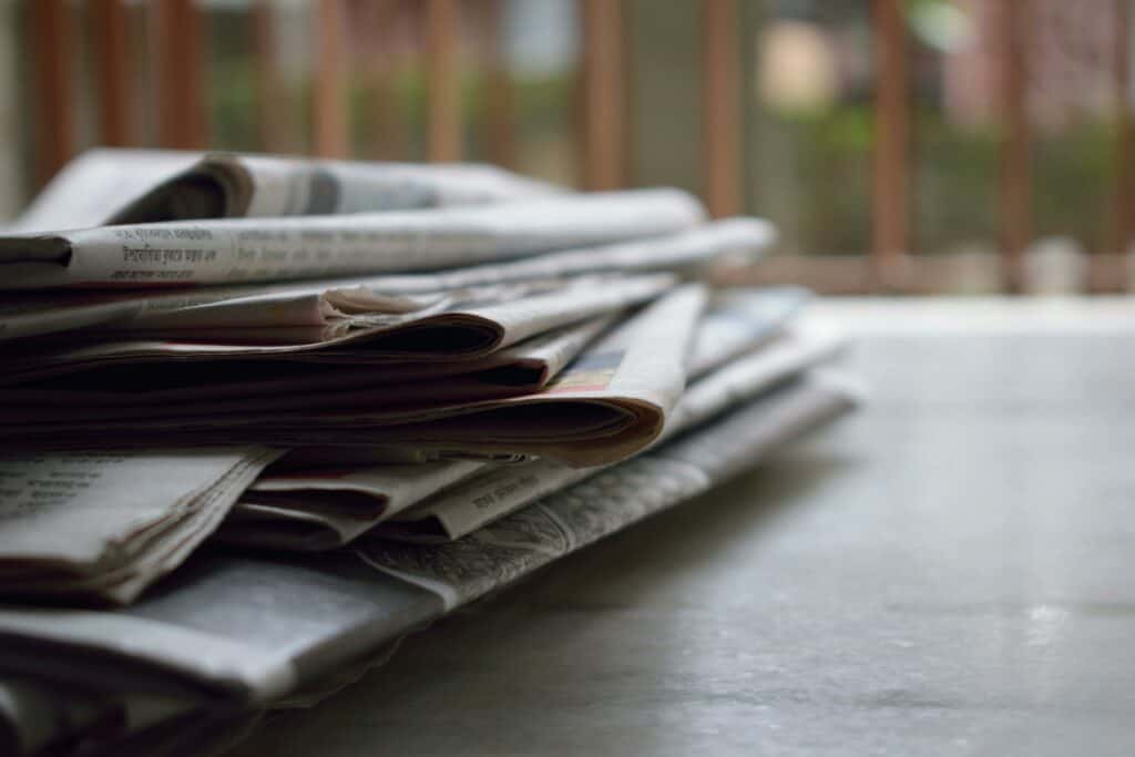 A stack of newspapers on a brown table.