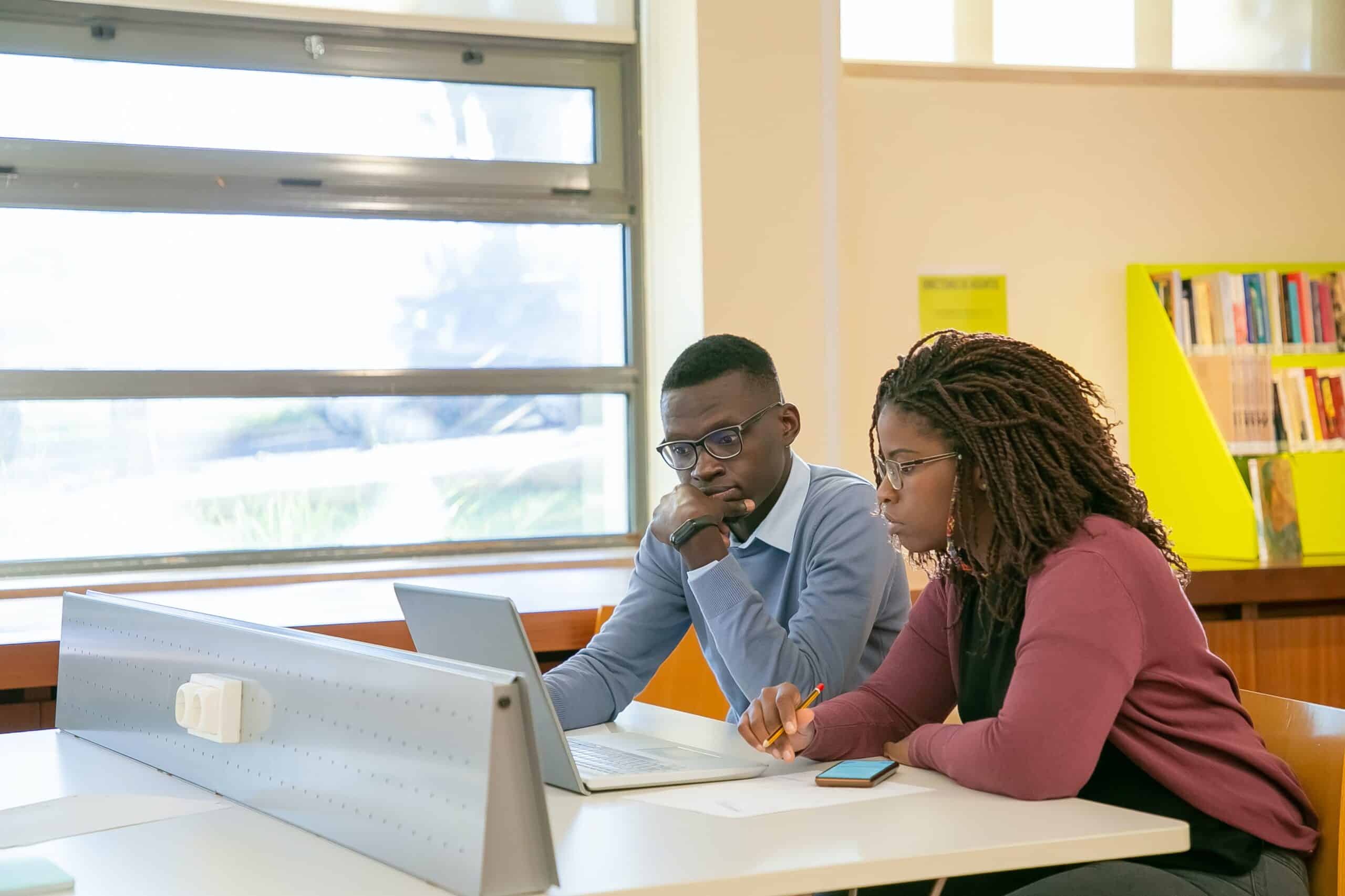 higher education enrollment marketing college students working on a laptop in a library